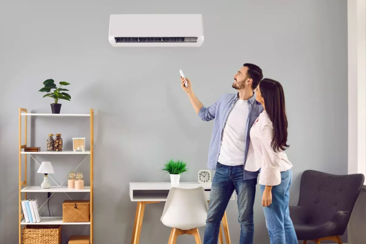 Couple adjusting a wall-mounted air conditioner with remote control