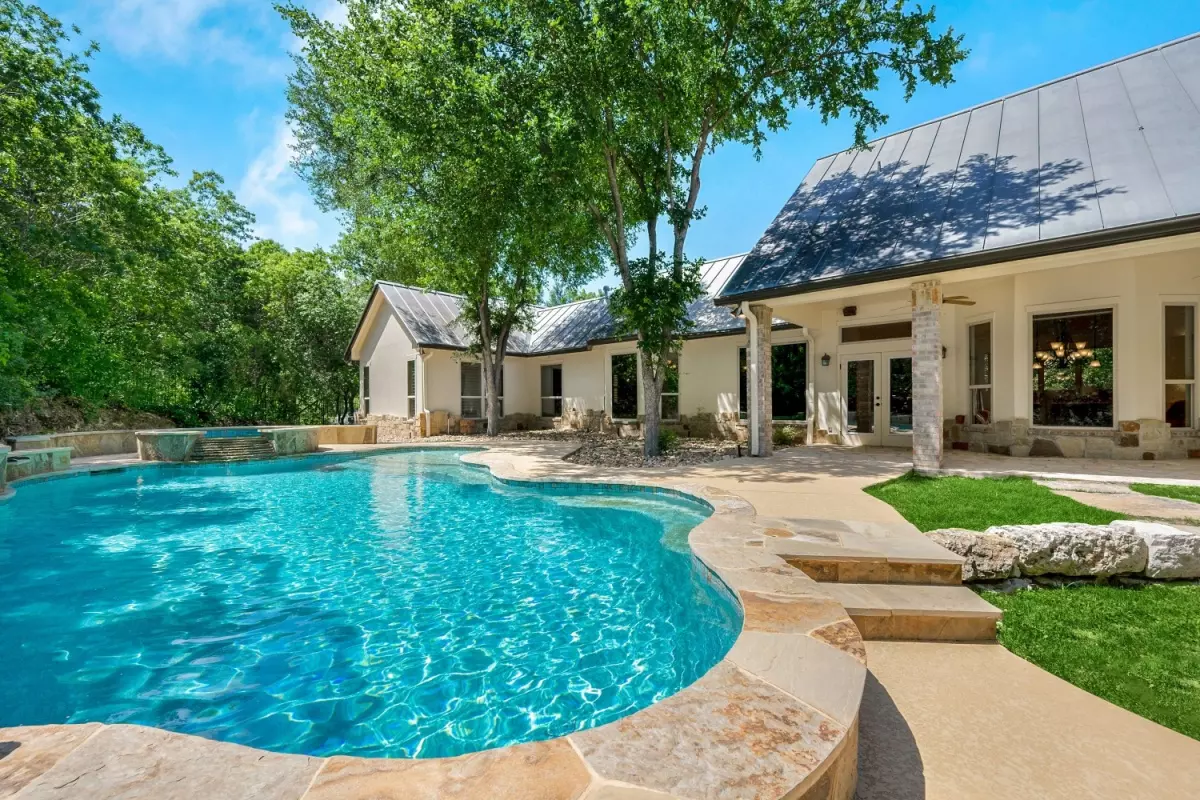 Luxurious backyard with a fiberglass pool surrounded by lush greenery and a modern home