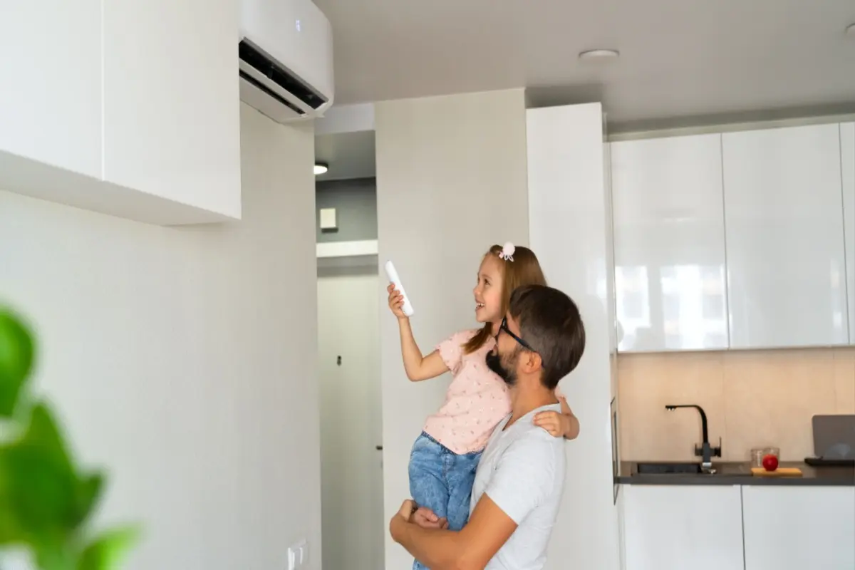 Father and daughter in front of the new installed air conditioner in their house 