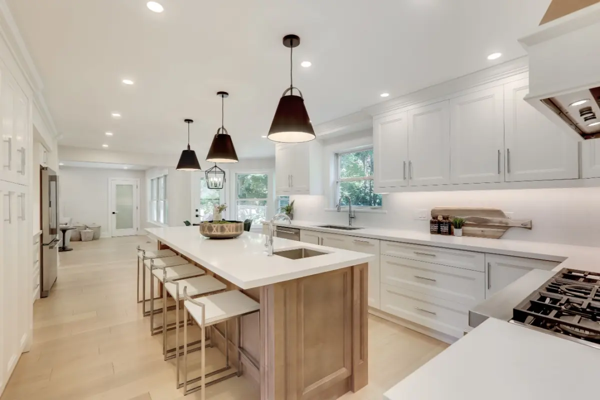 Modern kitchen style with white cabinets, white island, and lights