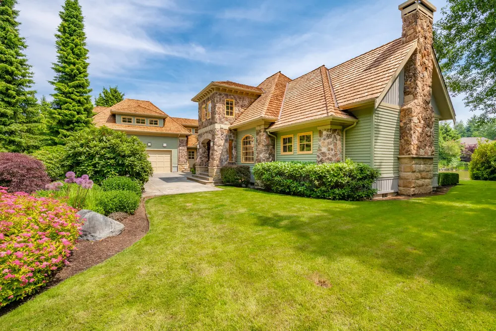 Cedar shake roof on a stone-and-siding home with landscaped front gardens.