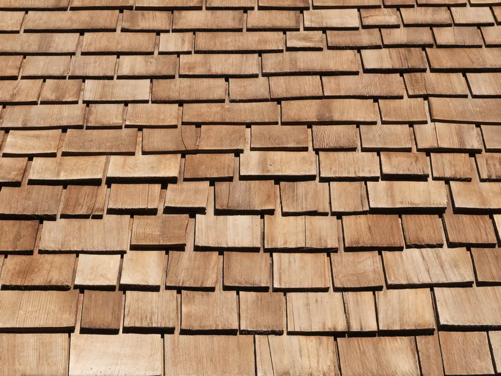 Close-up of overlapping cedar roof shakes showing varied widths, wood grain, and warm brown tones.