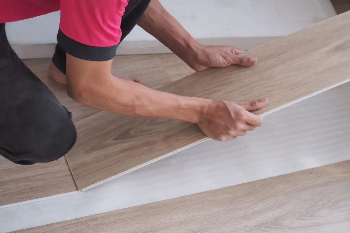Close up of man hands laying laminate wooden planks on the floor in apartment.