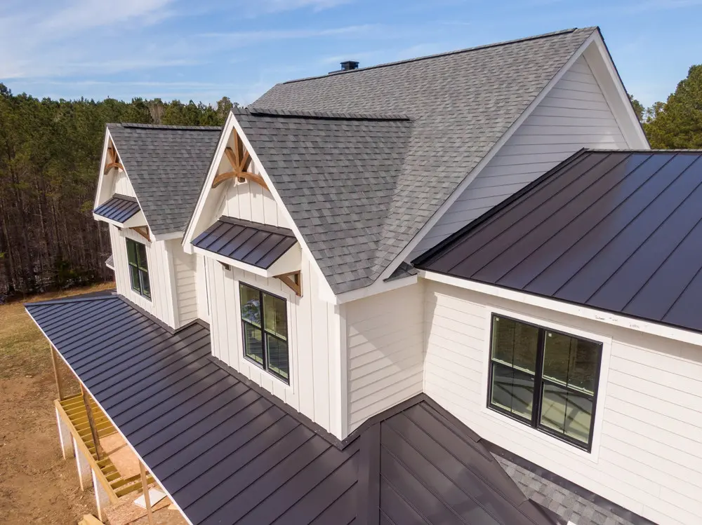 Residential roof combining architectural asphalt shingles with standing-seam metal accents