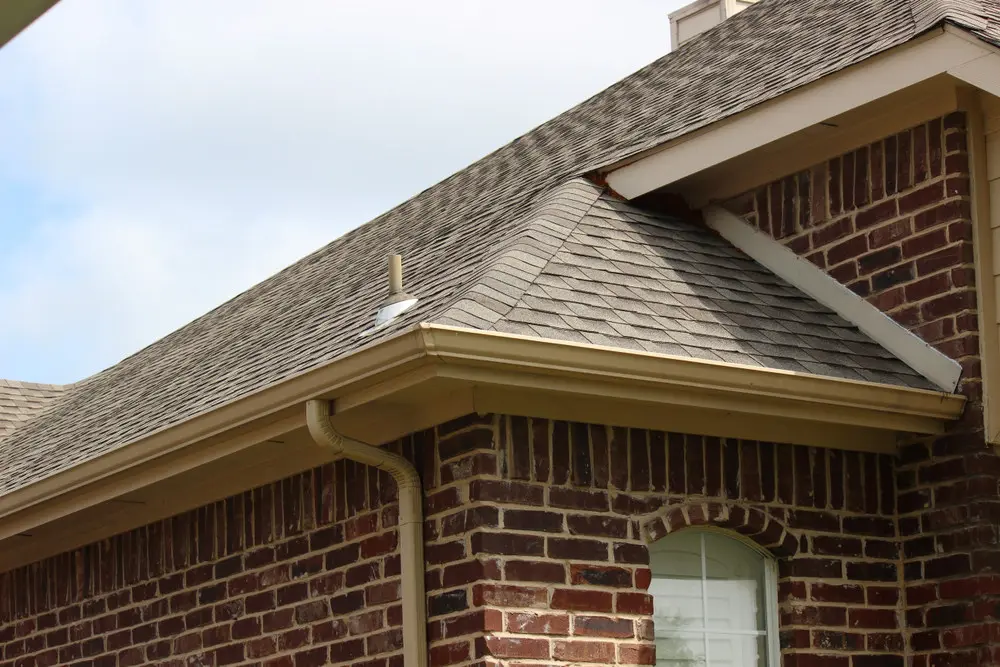 Finished gutter and downspout system on a brick house with an asphalt-shingle roof