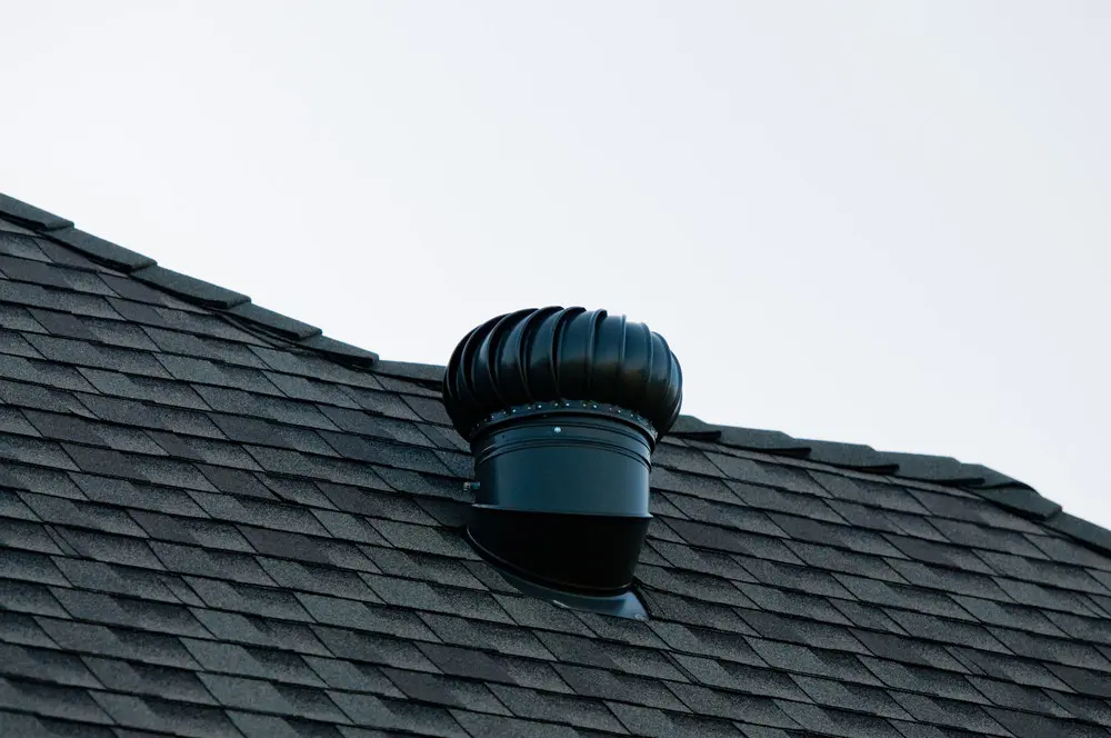 Turbine vent on a black asphalt-tiled roof.