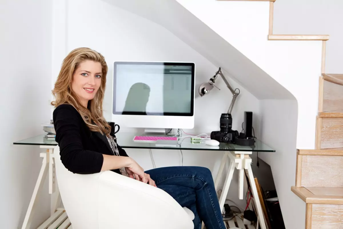 Woman sitting at desk under stairs